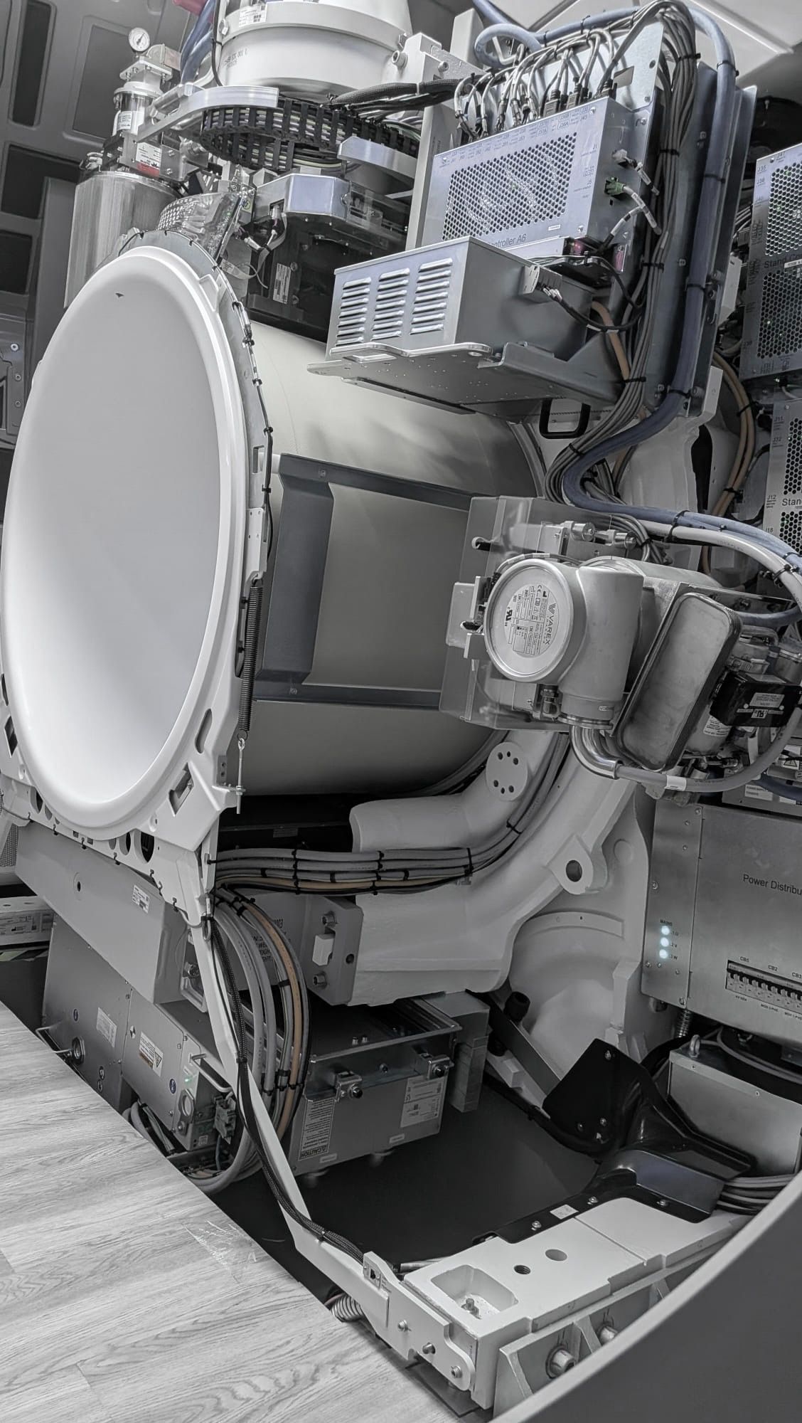 Computertomograph im Aufbau mit geöffneter Gantry: Röntgenröhre, Kühl- und Hochspannungstechnik, die Stromverteilung des Geräts und gebündelte Leitungen.
